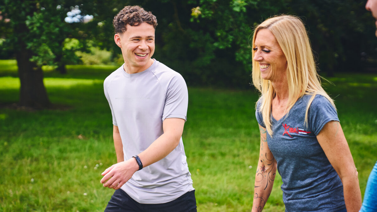 Joseph and Rach walking up a green, grassy hill. Talking to each other and smiling.