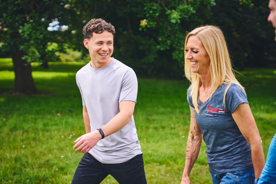 Joseph and Rach walking up a green, grassy hill. Talking to each other and smiling.