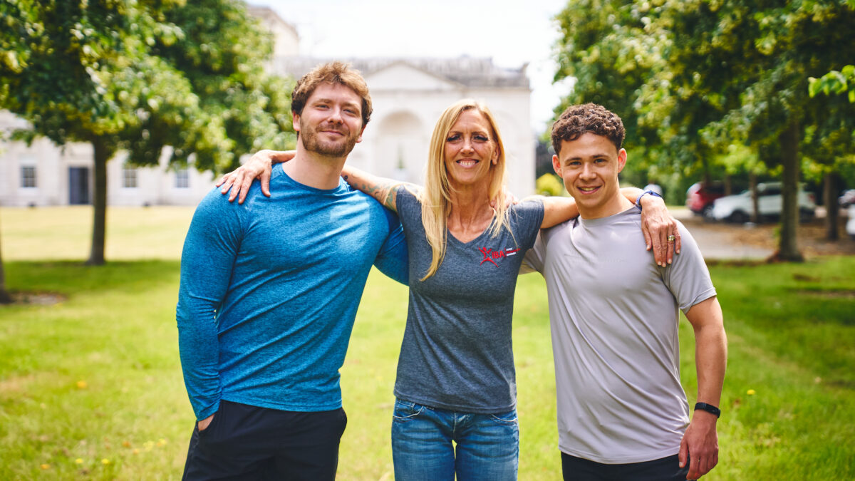 Rcah, Tom and Joseph are looking at the camera and smiling. They are stood in a field, Rach is in the middle, and the boys either side. All smiling at the camera.