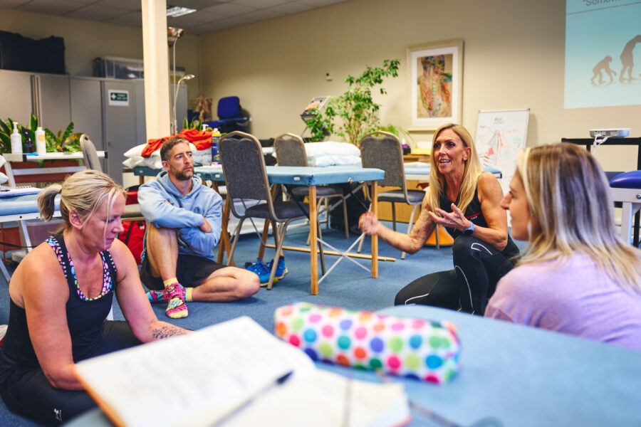 Rachel teaching three people all sat on the floor and talking.